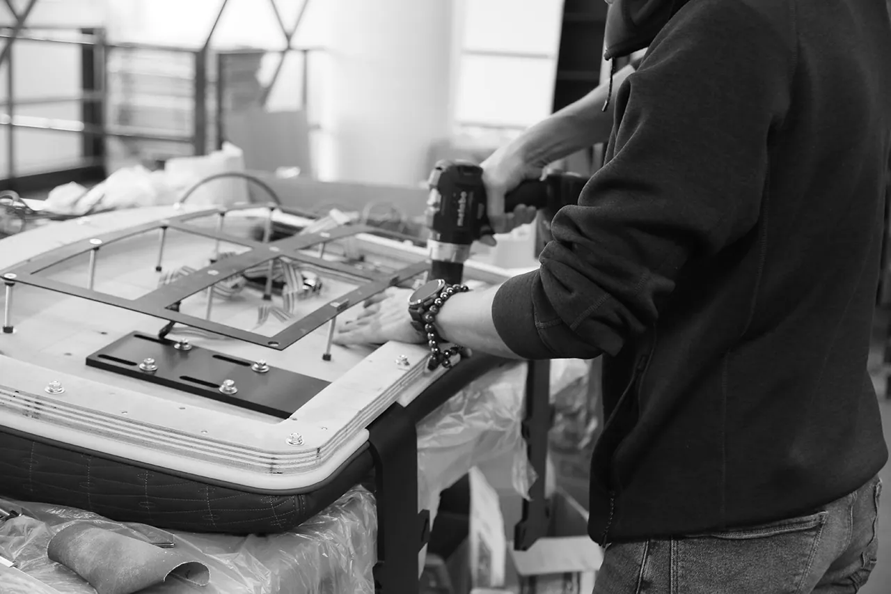 A poker table top being assembled by hand in the MGR workshop (b&w)
